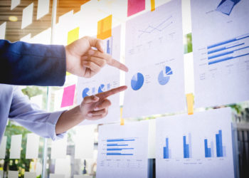 business People wit the board and finance data on it.