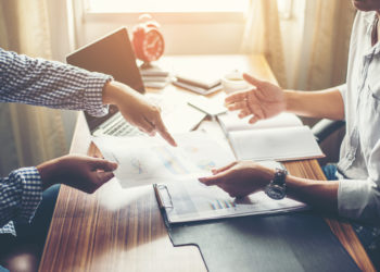 people at the table talking about business and exchanging the documents