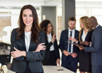 Business woman in black suite standing at the meeting with other men
