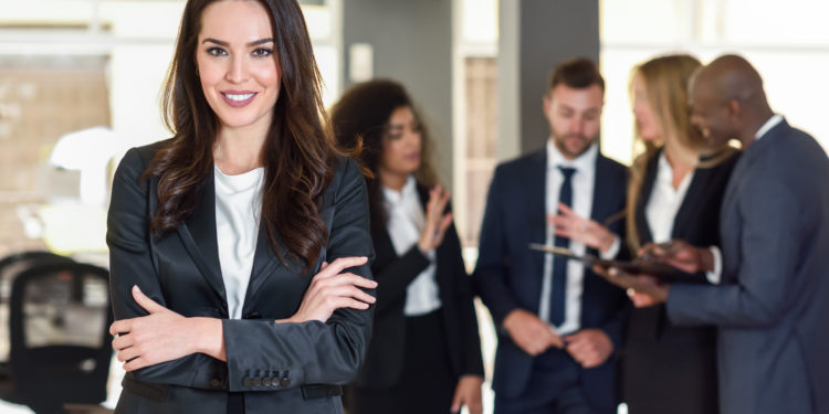 Business woman in black suite standing at the meeting with other men