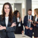 Business woman in black suite standing at the meeting with other men