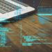 laptop on the table with hacking code