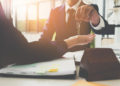 Property Manager Giving House Keys To Woman And Sign Agreement In Office