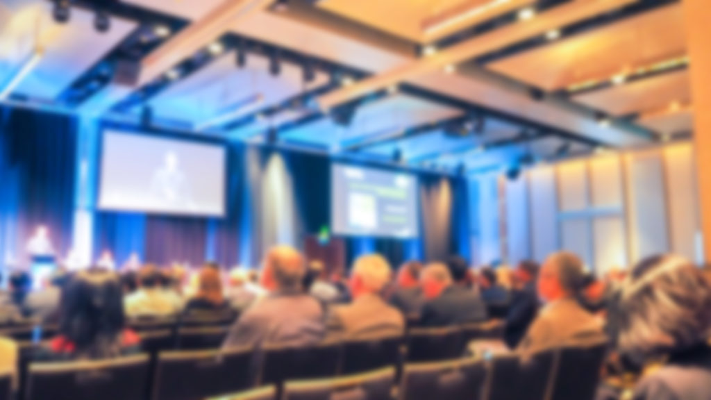 Blured Conference Room With A Person Presenting To The Audience