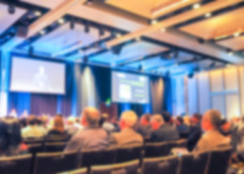 Blured Conference Room With A Person Presenting To The Audience