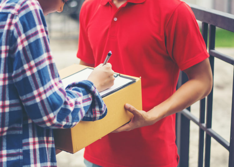 Young Man Delivering Package To Customer At Home. Delivery