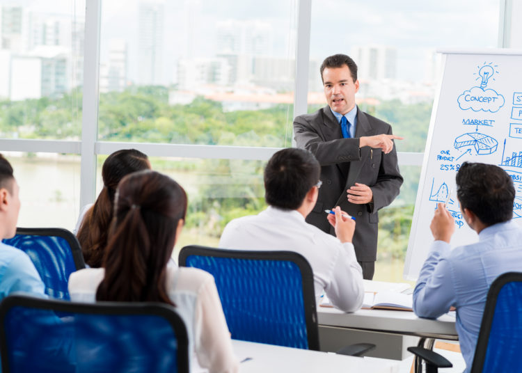 Middle-aged businessman conducting seminar for his colleagues