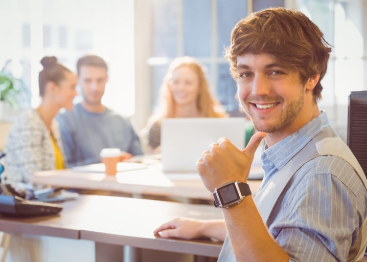 Portrait of smiling young businessman with colleagues in the office