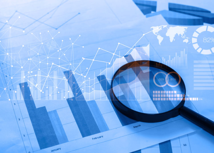 Magnifying glass and documents with analytics data lying on table,selective focus