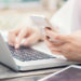 Female hands on laptop keyboard and holding smart phone, selective focus with shallow depth of field, soft vintage color tone