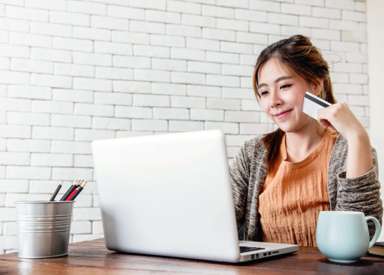 Young Woman Shopping with Credit Card and Laptop at Home, Happy Female Buying Products via Online