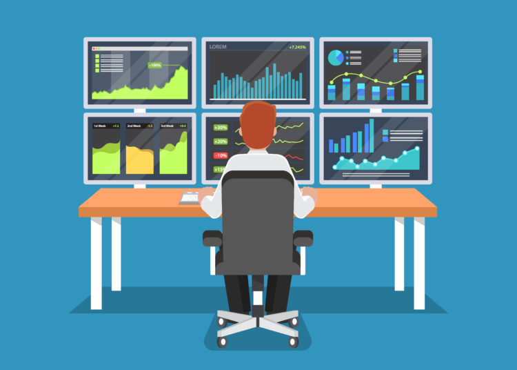 Businessman Or Stock Market Trader Working At Desk With Six Monitor Showing Data.