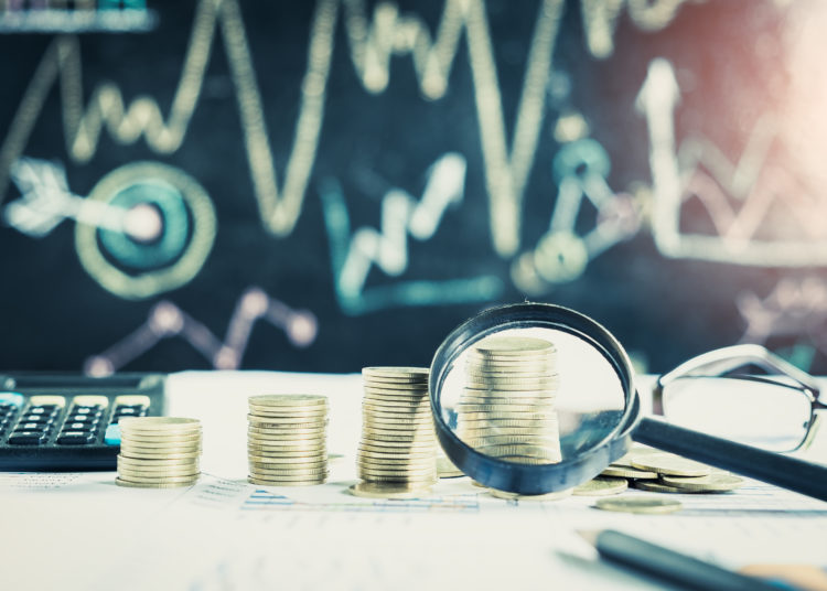 Magnifying glass, pencil and calculator on financial chart and g