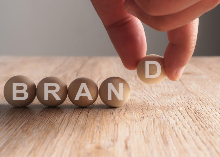 Hand putting on brand word written in wooden ball