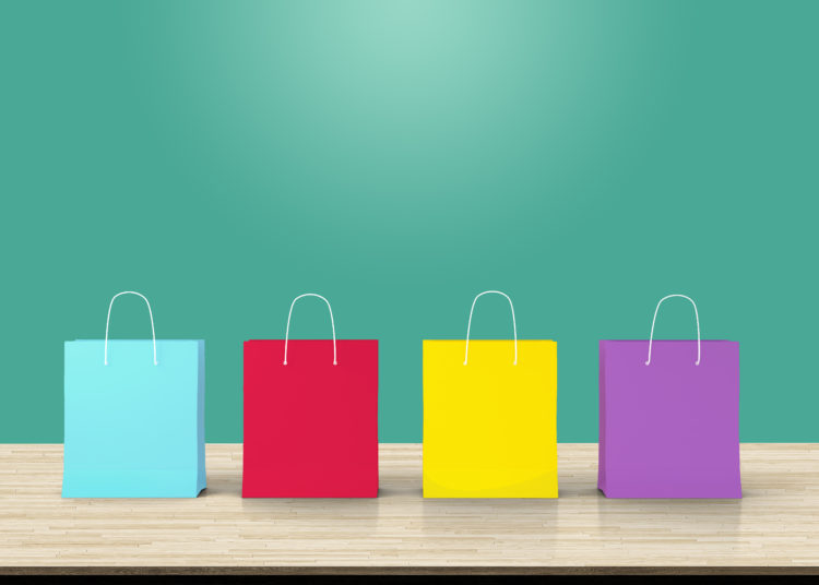 Four paper shopping bags on wood table backdrop. Concept about online shopping or E-commerce that everything can be bought easily by using an internet.