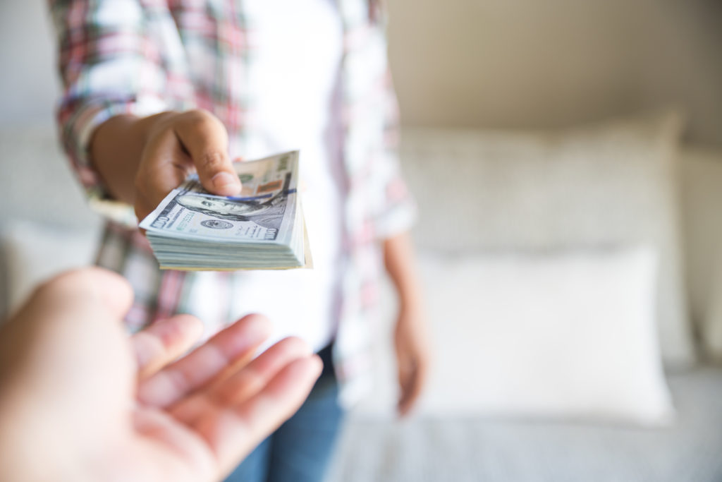 Soft focus on woman hands proposing money us dollar bills to you.