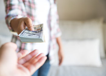Soft focus on woman hands proposing money us dollar bills to you.