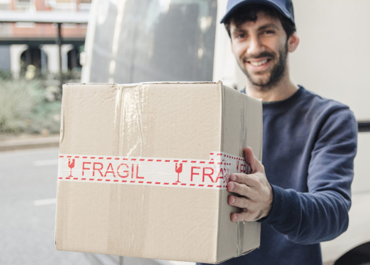 Delivery man unloading cardboard box from vehicle