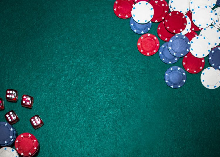 Casino chips and red dices on green poker backdrop