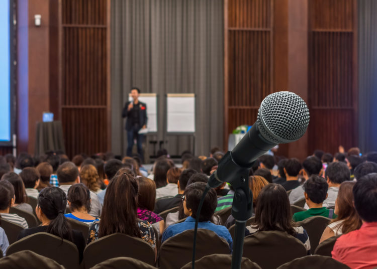 Microphone over the Abstract blurred photo of conference hall or seminar room with attendee background, Business meeting concept