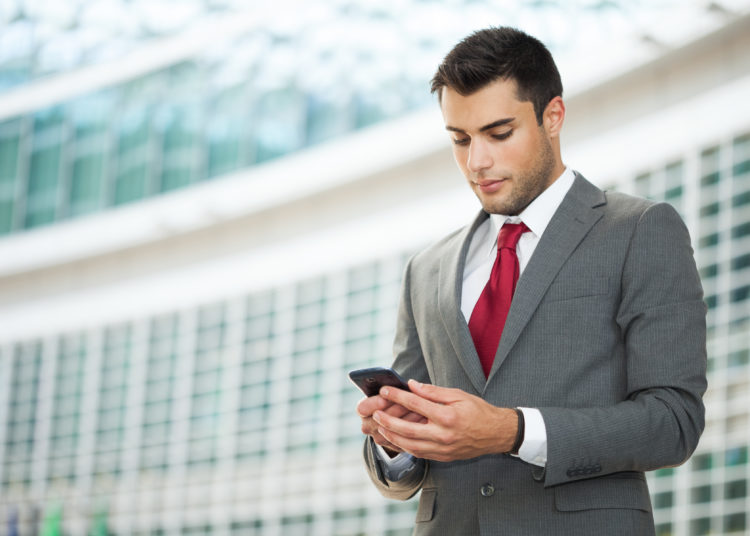 Young businessman using his mobile phone. Copy-space on the left