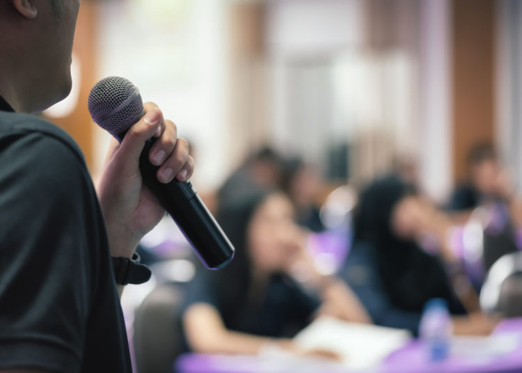 Microphone over the Abstract blurred photo of conference hall or seminar room with attendee background, Business meeting concept