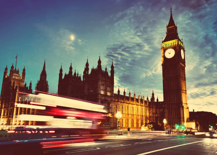 Red bus in motion, Big Ben and Westminster Palace in London, the UK. at night. View from Westminster Bridge. Moon shining, vintage, retro.