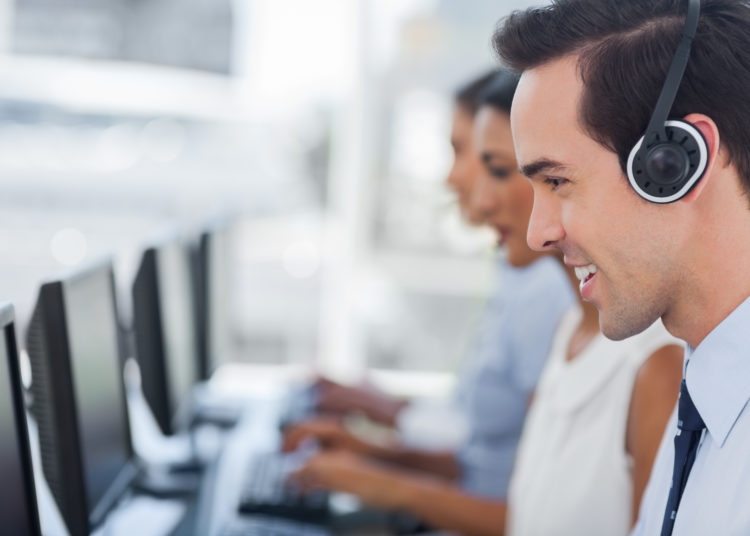 Focus on a smiling call centre agent working on computer