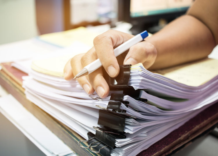 Businessman hands searching nfinished documents stacks of paper files on office desk for report papers, piles of unfinish papers sheet achieves with clips indoor, Document is written, drawn,presented.