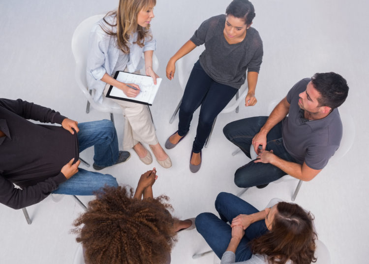 Patients listening to each other in group session sitting in circle