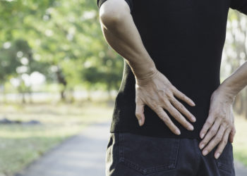 A woman suffering from backache, spinal injury and muscle issue problem at outdoor.