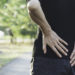 A woman suffering from backache, spinal injury and muscle issue problem at outdoor.