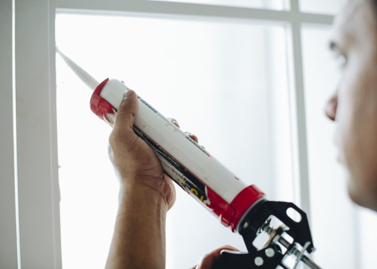 Man using a silicone gun to repair a window