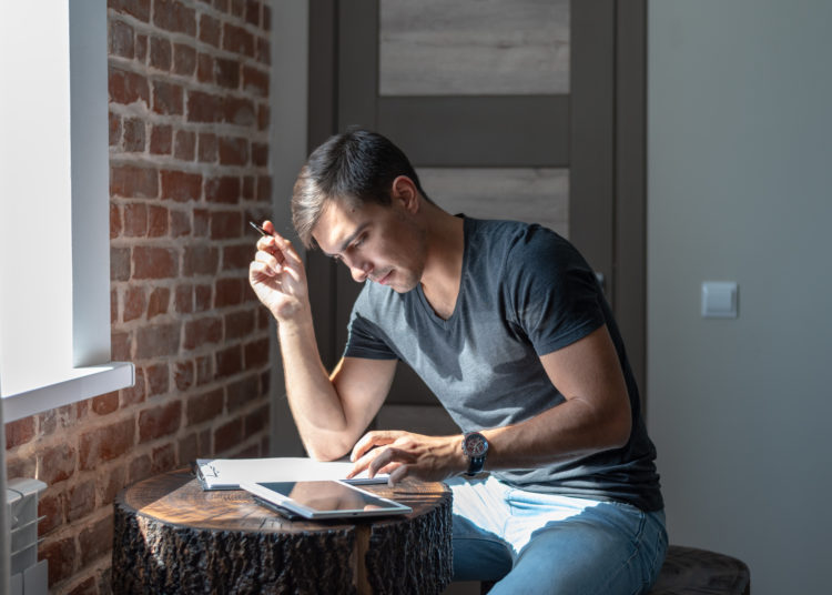 man at table in front of window, uses tablet, work at home, freelance, business plan, startup