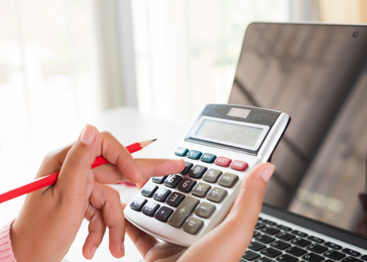 woman hand holding red pencil and working with calculator, business document and laptop computer notebook