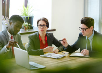 Financial managers looking at online data while discussing new project