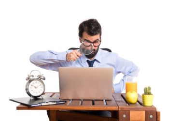 Businessman in his office with magnifying glass