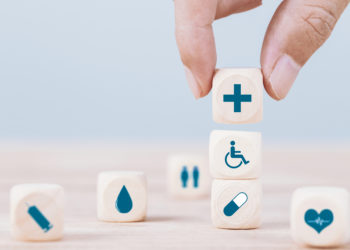 Hand chooses a emoticon icons healthcare medical symbol on wooden block , Healthcare and medical Insurance concept