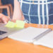 Woman hand working at a computer and writing on a notepad with a pen in the office.Web banner.