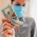 Coronavirus covid-19 pandemic pharmacy profit on medical masks. High prices for medicine. Woman holding dollars cash. Speculation