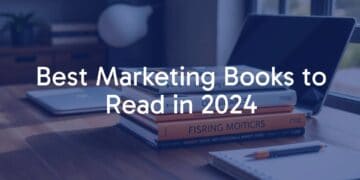 A stack of modern marketing books on a wooden desk, with a laptop and notebook beside them, natural daylight, cozy and professional atmosphere.